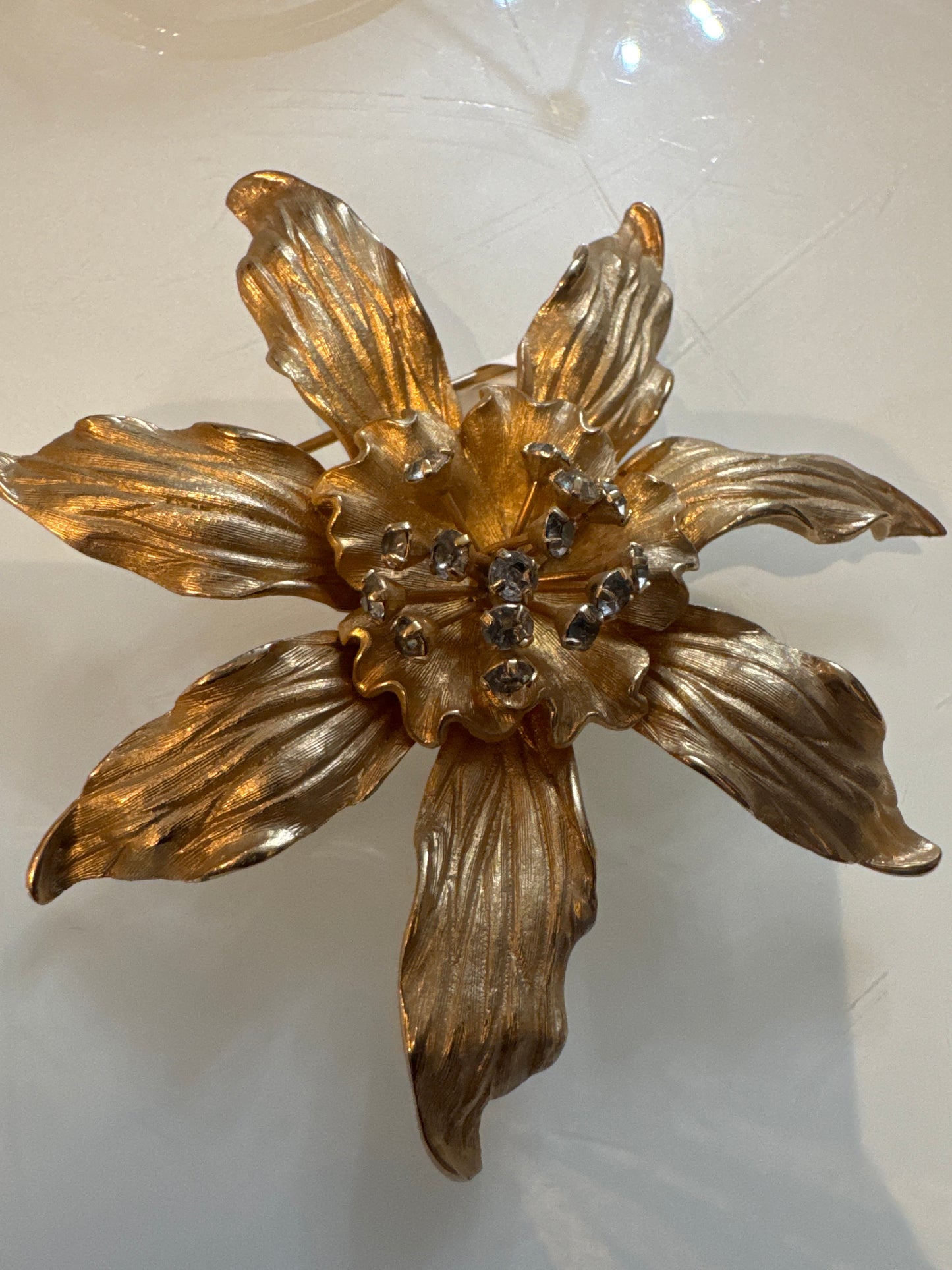 Beautiful gold tone flower brooch with rhinestone center