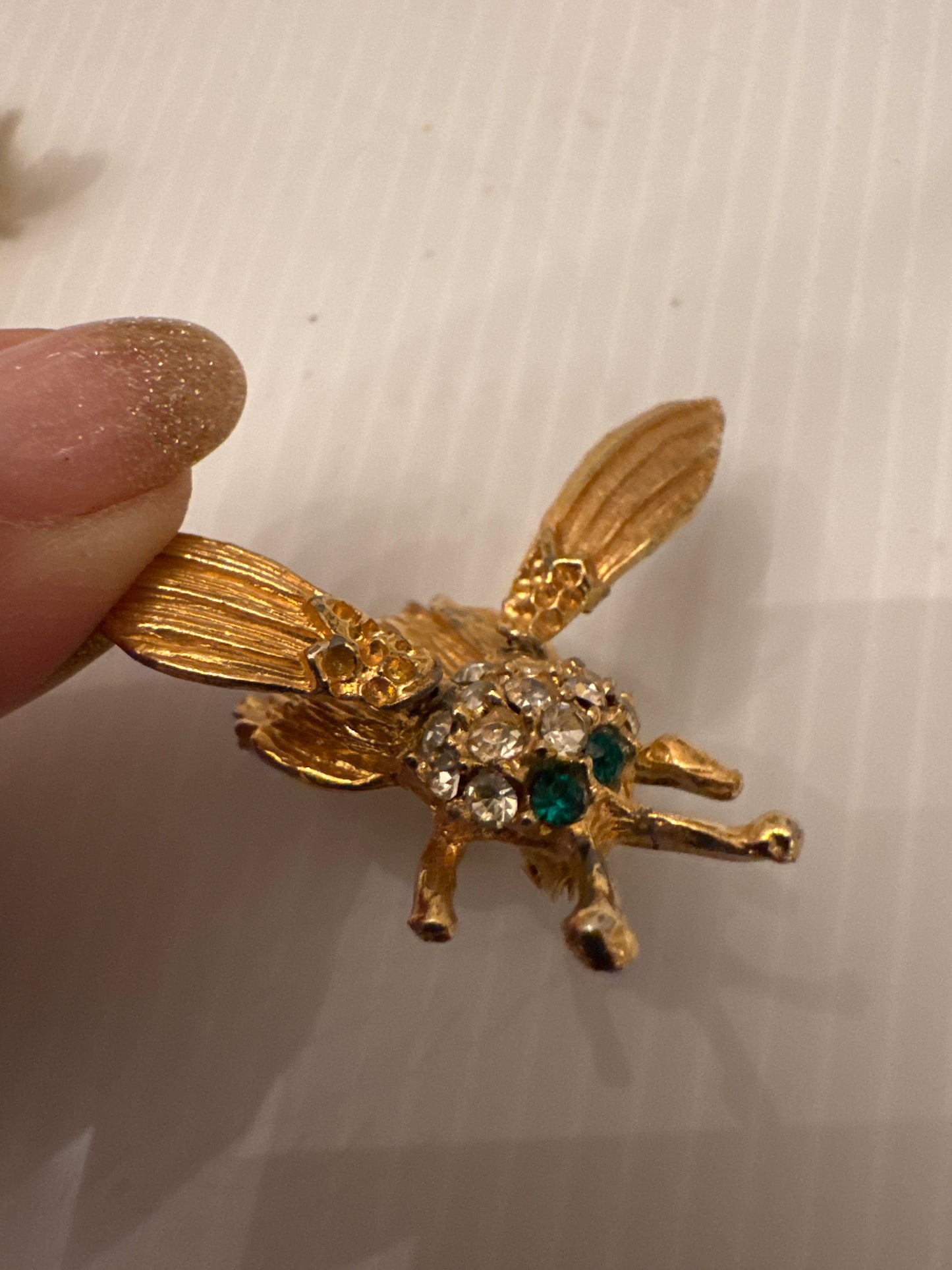 Unsigned vintage trembler brooch, attributed to Hattie Carnegie, circa late 1940s. Identified by its sculptural gold-tone body, ribbed wings, green crystal eyes, and classic Carnegie tremble construction.
