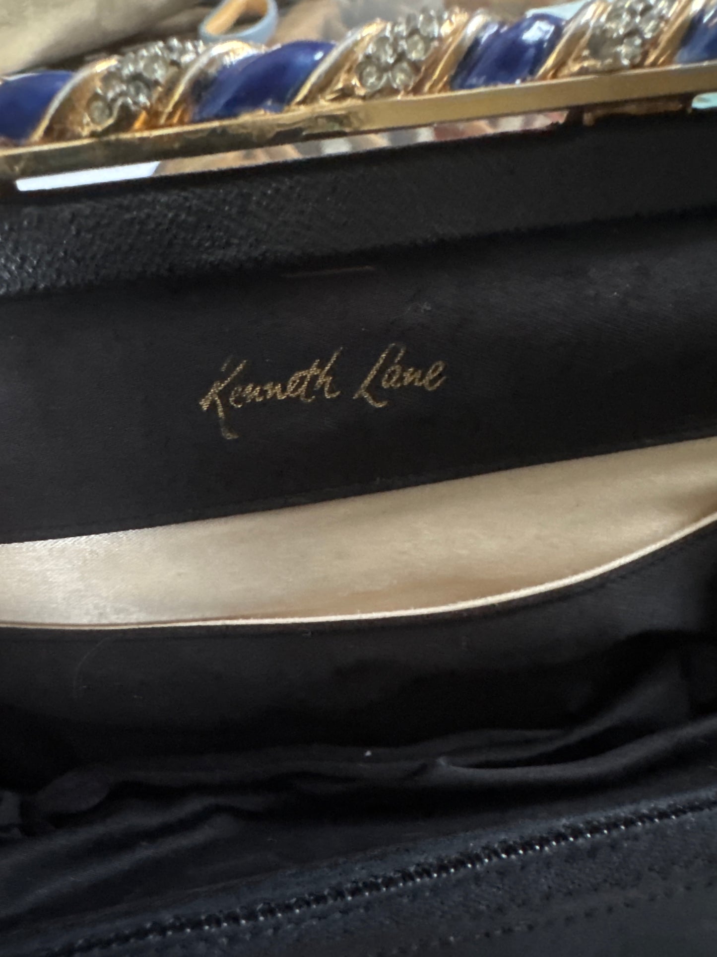 1960s signed Kenneth Lane black leather clutch with decorative blue enamel and rhinestone swirl frame
