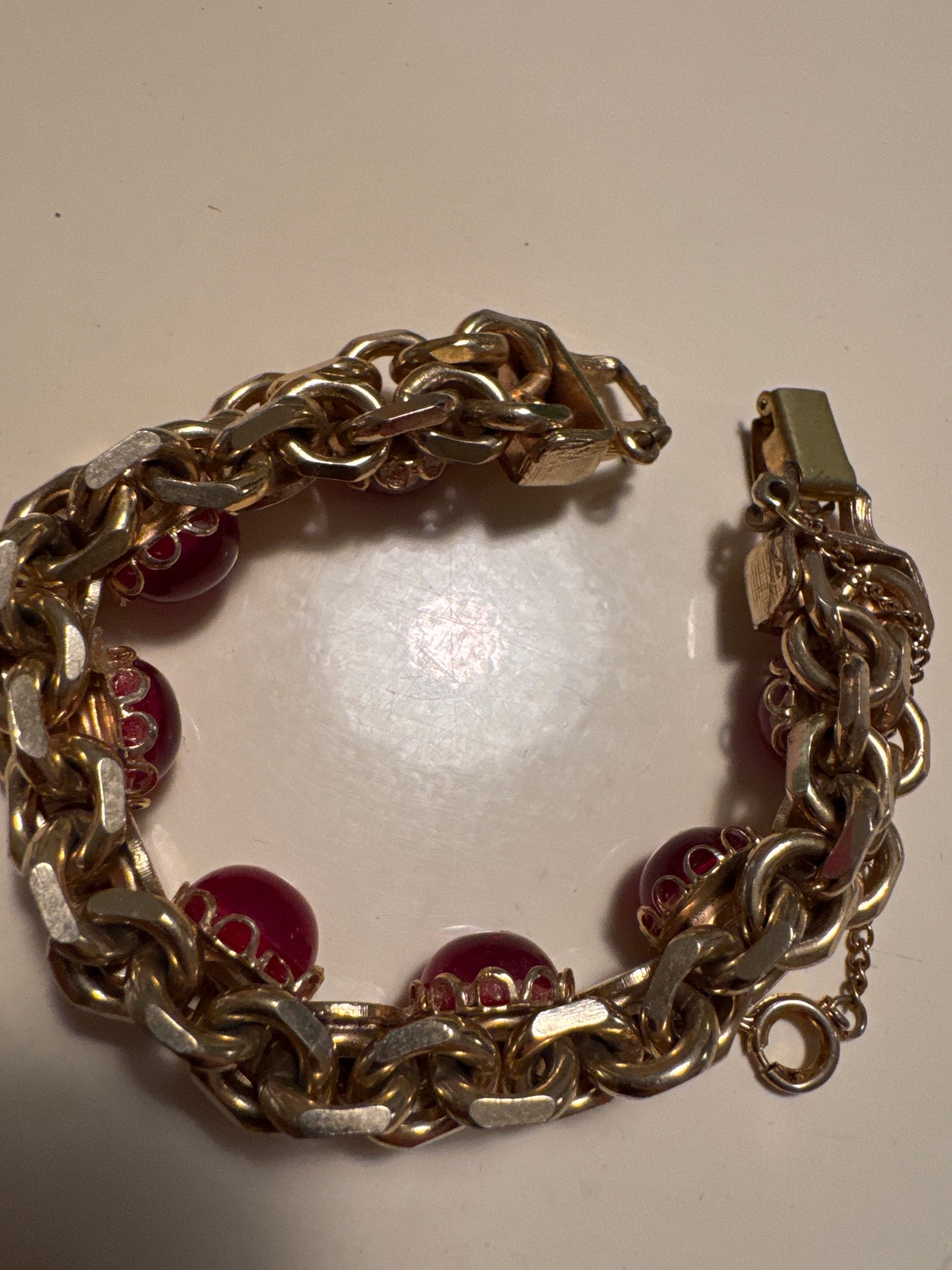 This bold and beautiful mid-century bracelet features rich ruby cabochons set against textured gold-tone links in a classic 1950s cocktail style. A glamorous statement piece that reflects the elegance and boldness of the post-war era