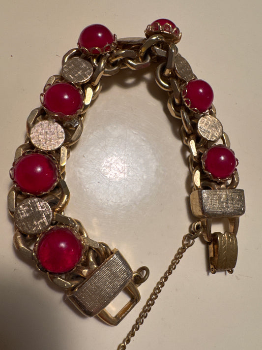 This bold and beautiful mid-century bracelet features rich ruby cabochons set against textured gold-tone links in a classic 1950s cocktail style. A glamorous statement piece that reflects the elegance and boldness of the post-war era