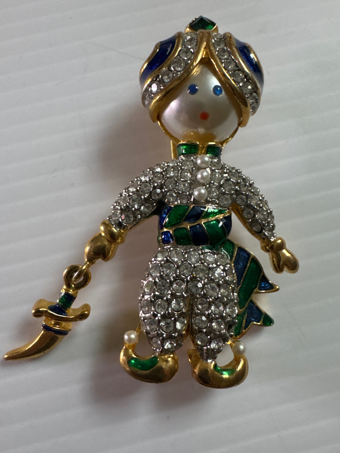 A whimsical 1980s vintage pair inspired by Arabian Nights fantasy—this figural duo features a genie and his companion, each richly detailed with hand-set rhinestones, enamel accents, and expressive pearlized faces.
