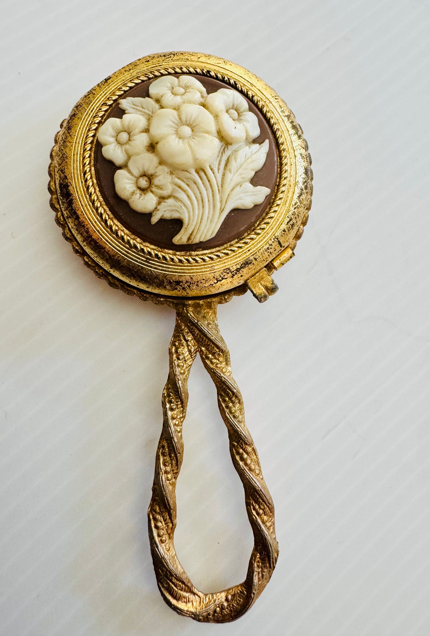 Beautiful vintage Makeup powder compact with inside and outside mirror. Gold tone handle, and flower cameo cover. Sourced in Paris.