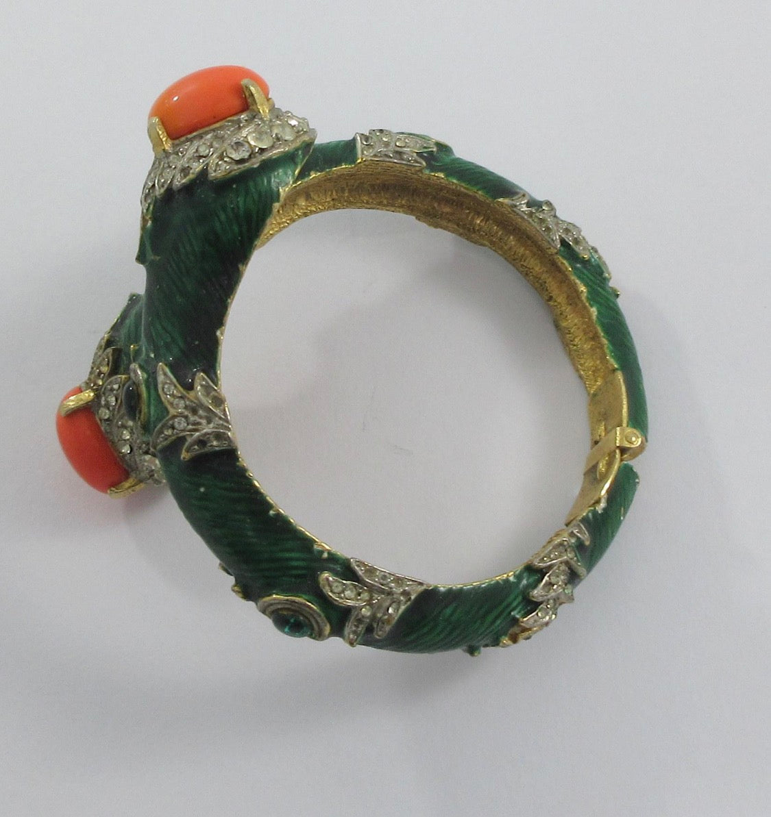 Unsigned Gold tone clamper bracelet with green enamel, rhinestone, faux coral cabochons and green cabochons attributed to Kenneth J Lane mid 1960s