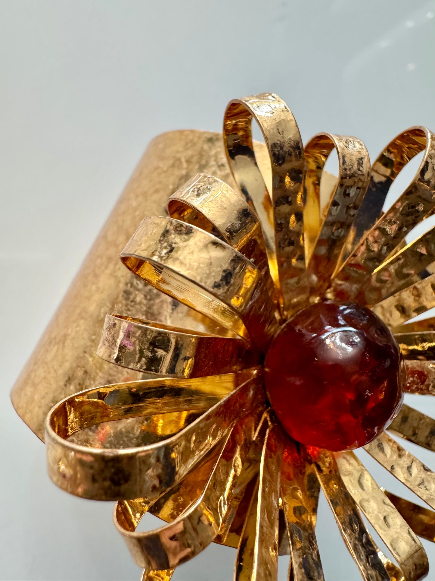 Adjustable hammered goldtone starburst cuff with red center stone