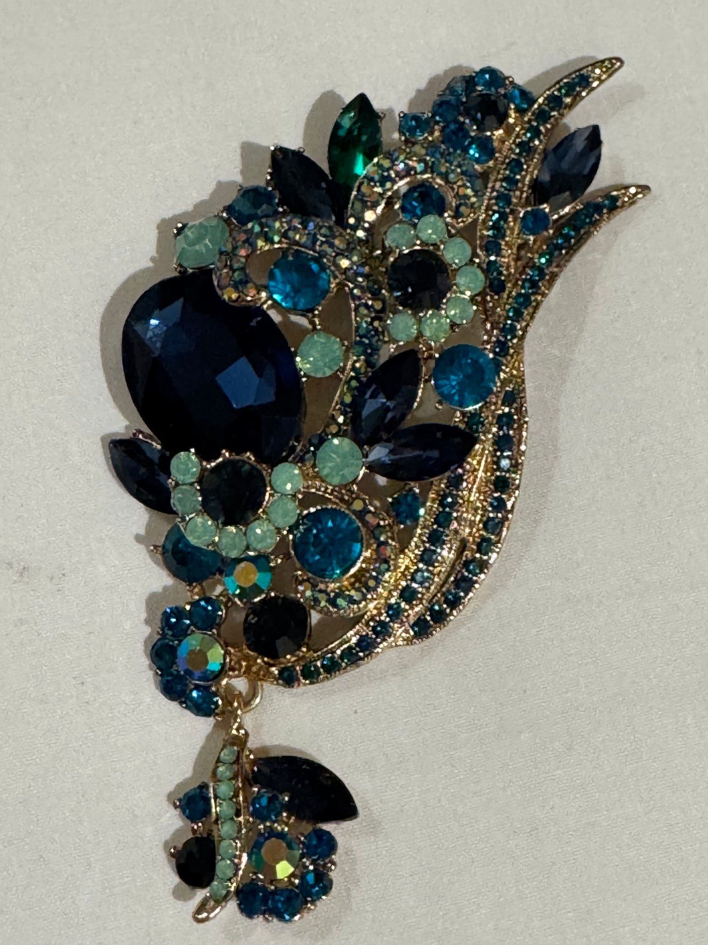 Jumbo 1980s rhinestone brooch with blue turquoise, light, green rhinestones and a dangling rhinestone on the bottom. Sourced in Paris.