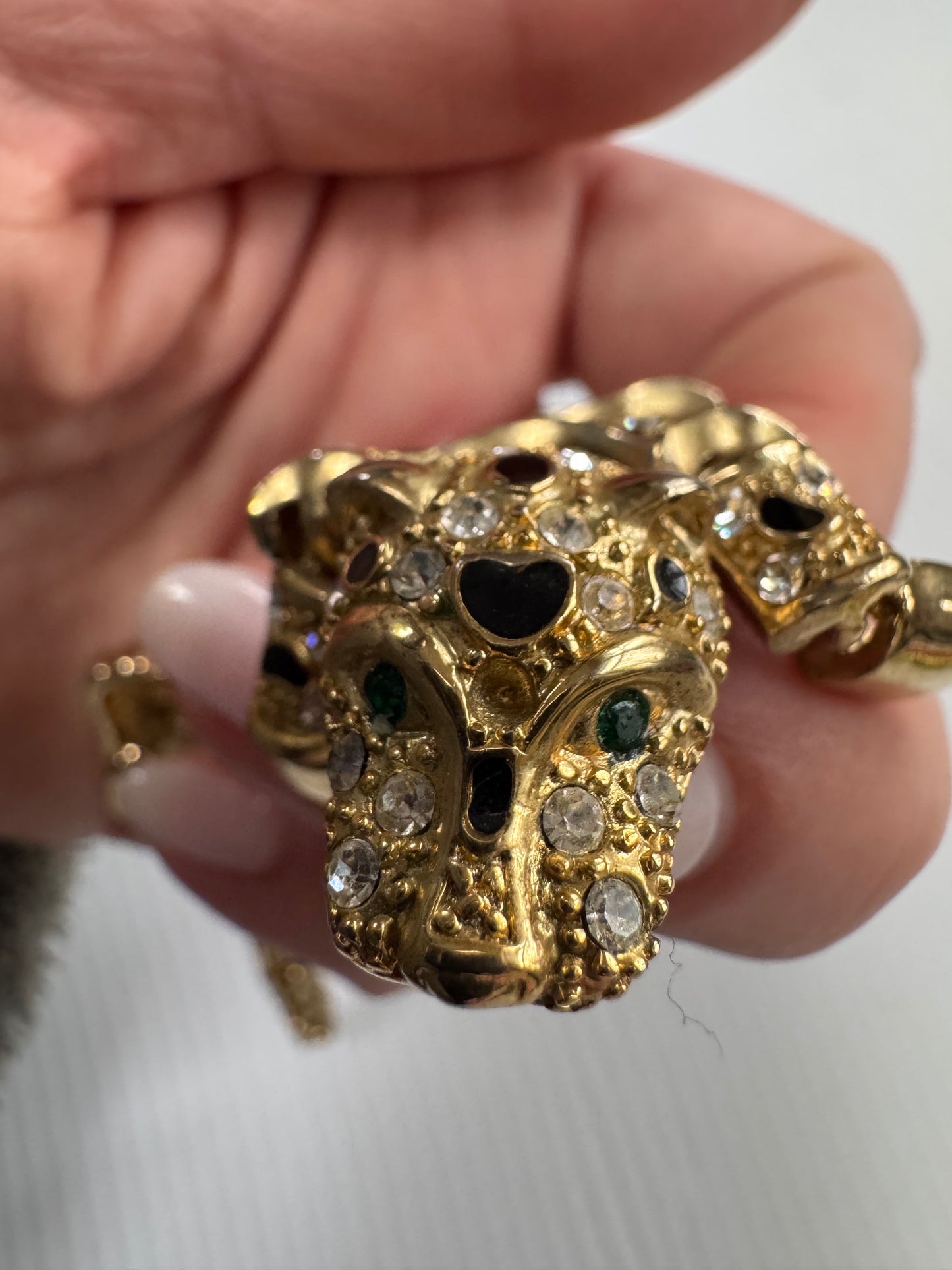 Vintage articulated leopard shoulder brooch in gold tone with black enamel and green rhinestone eyes