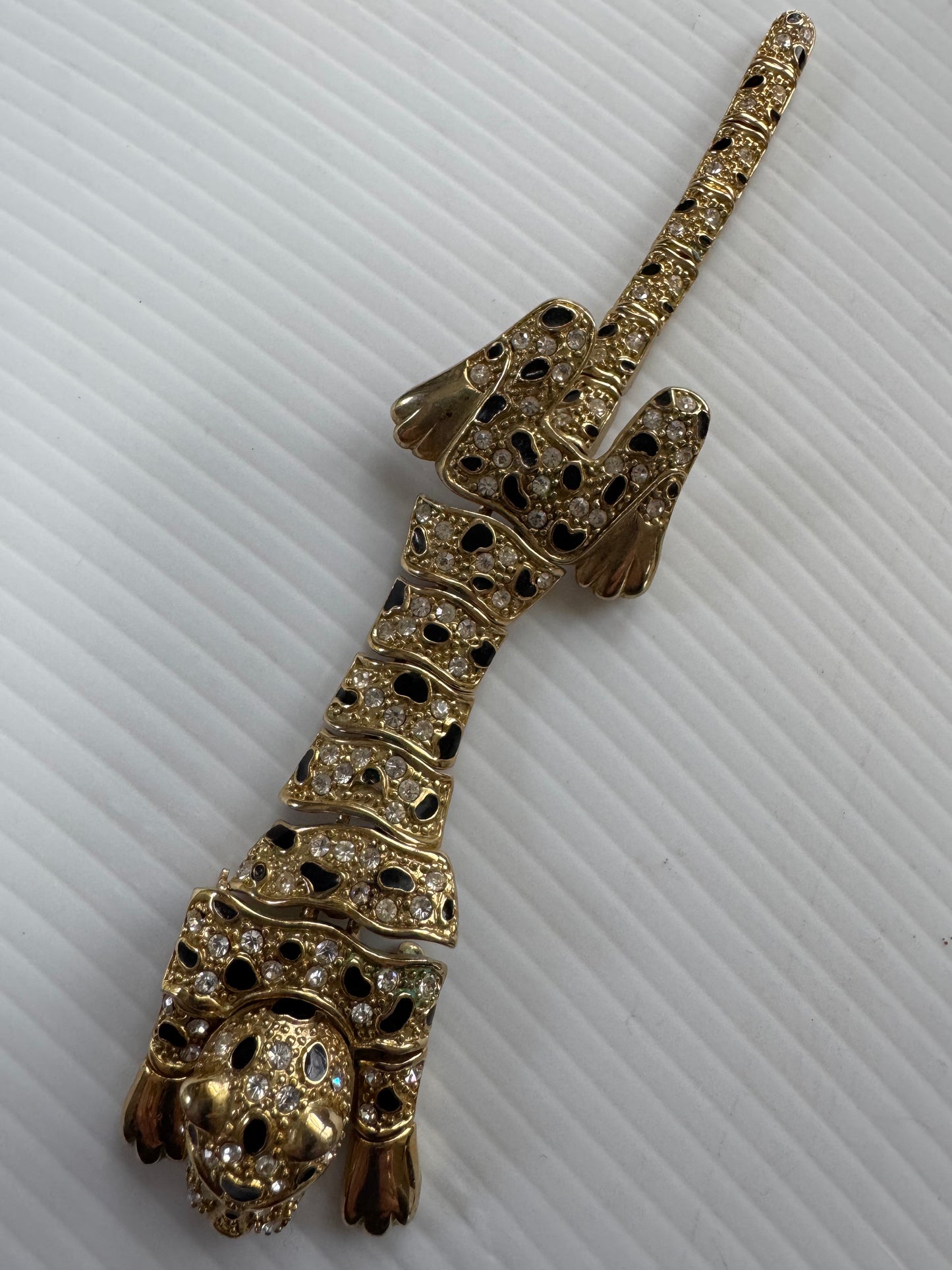 Vintage articulated leopard shoulder brooch in gold tone with black enamel and green rhinestone eyes