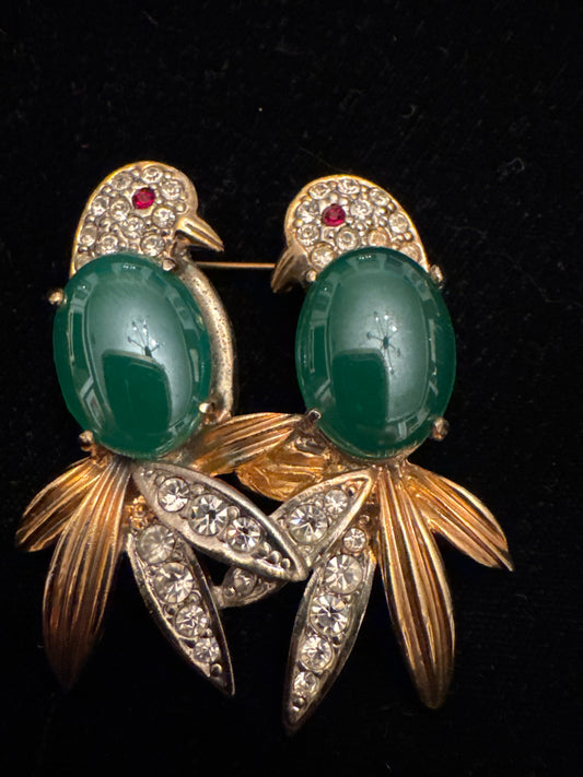 1940s vintage brooch featuring two birds perched closely together. Green molded glass cabochons, clear rhinestones, red eye accents. Czech glass France
