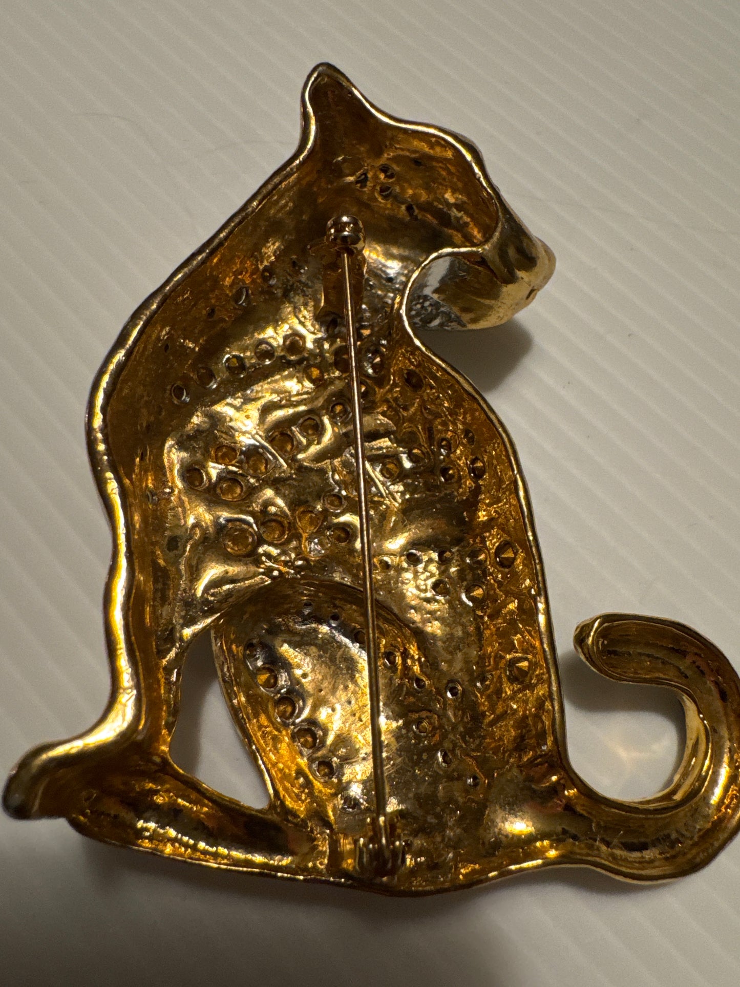 1980s jumbo gold tone, black enamel, and clear rhinestone cheetah brooch with green emerald eyes