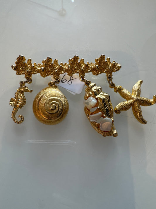 1980s gold tone, seashell bar brooch with seahorse, snail shells, and starfish charms