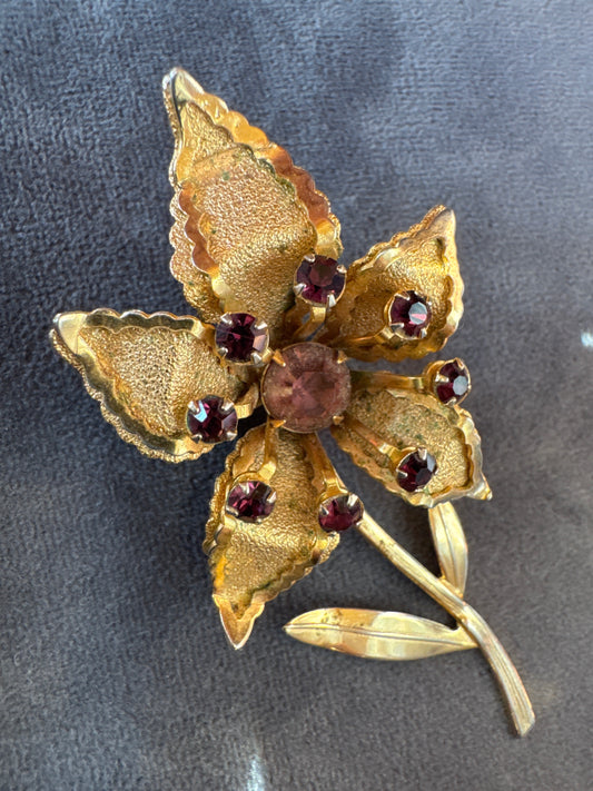 Gold tone and amethyst colored rhinestone flower brooch