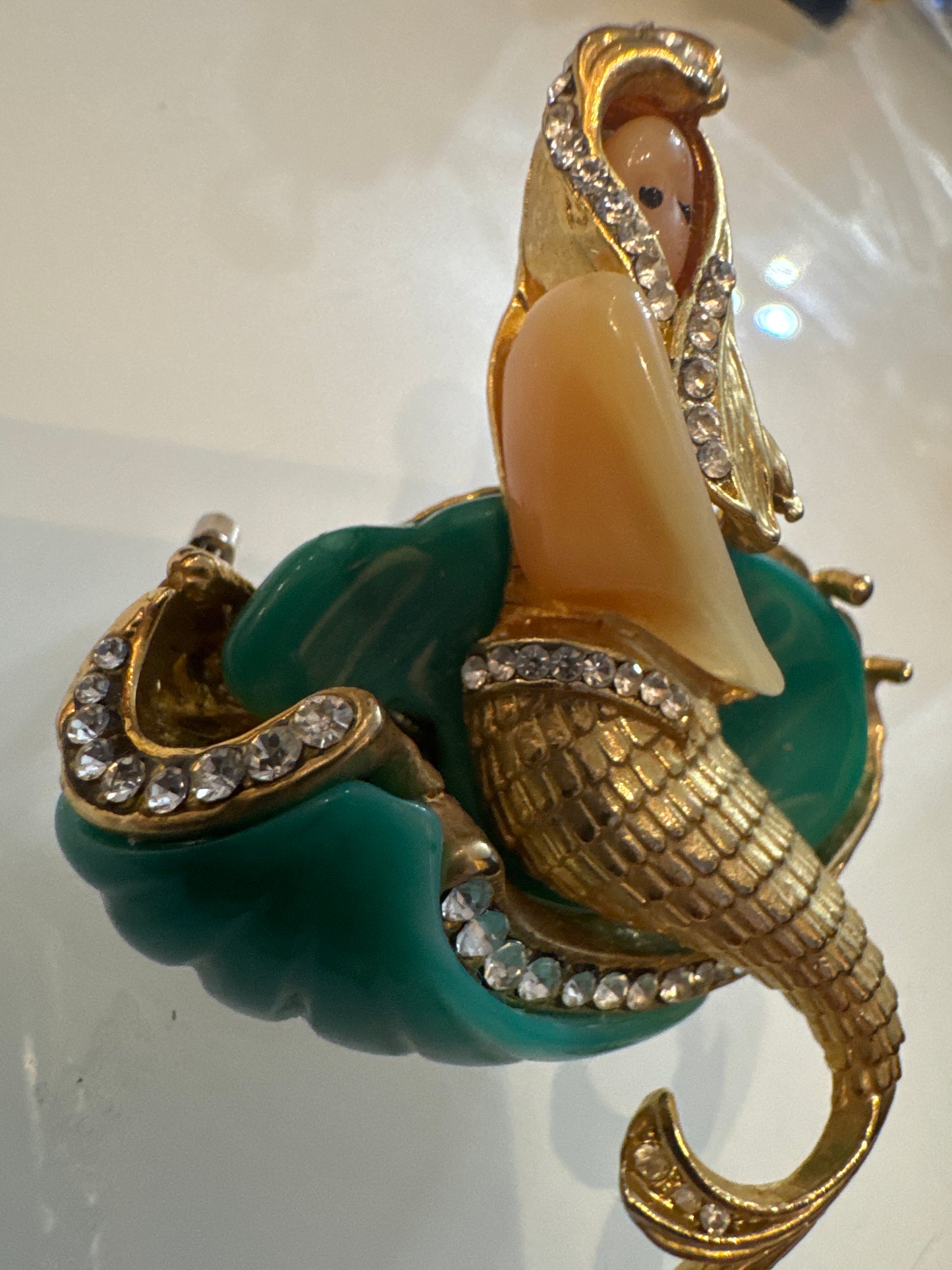 Attributed Hattie Carnagie mermaid brooch circa1960.
Carved lucite figure and wave, hand-set rhinestones, sculptural gold-tone metal. Unsigned, a strong example of mid-century fantasy figural jewelry.