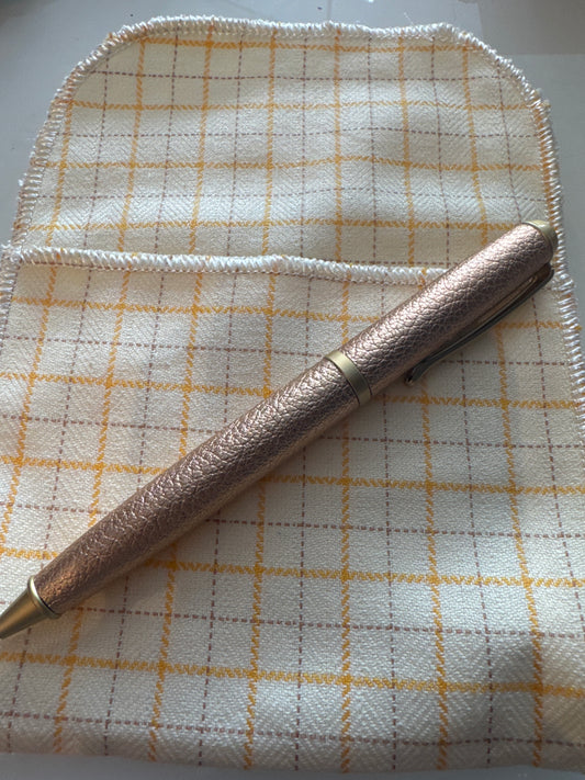 Rose gold leather pen with black ink.