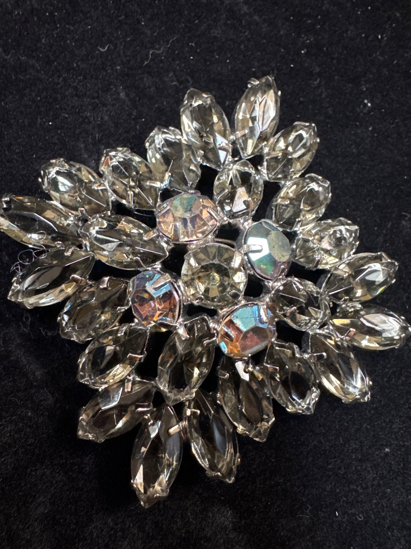 Beautiful 1950s Juliana brooch ~ slightly-domed silvertone metal and adorned by a burst of clear grey open-backed navettes.  In the center are five dark Aurora Borealis stones. NYC