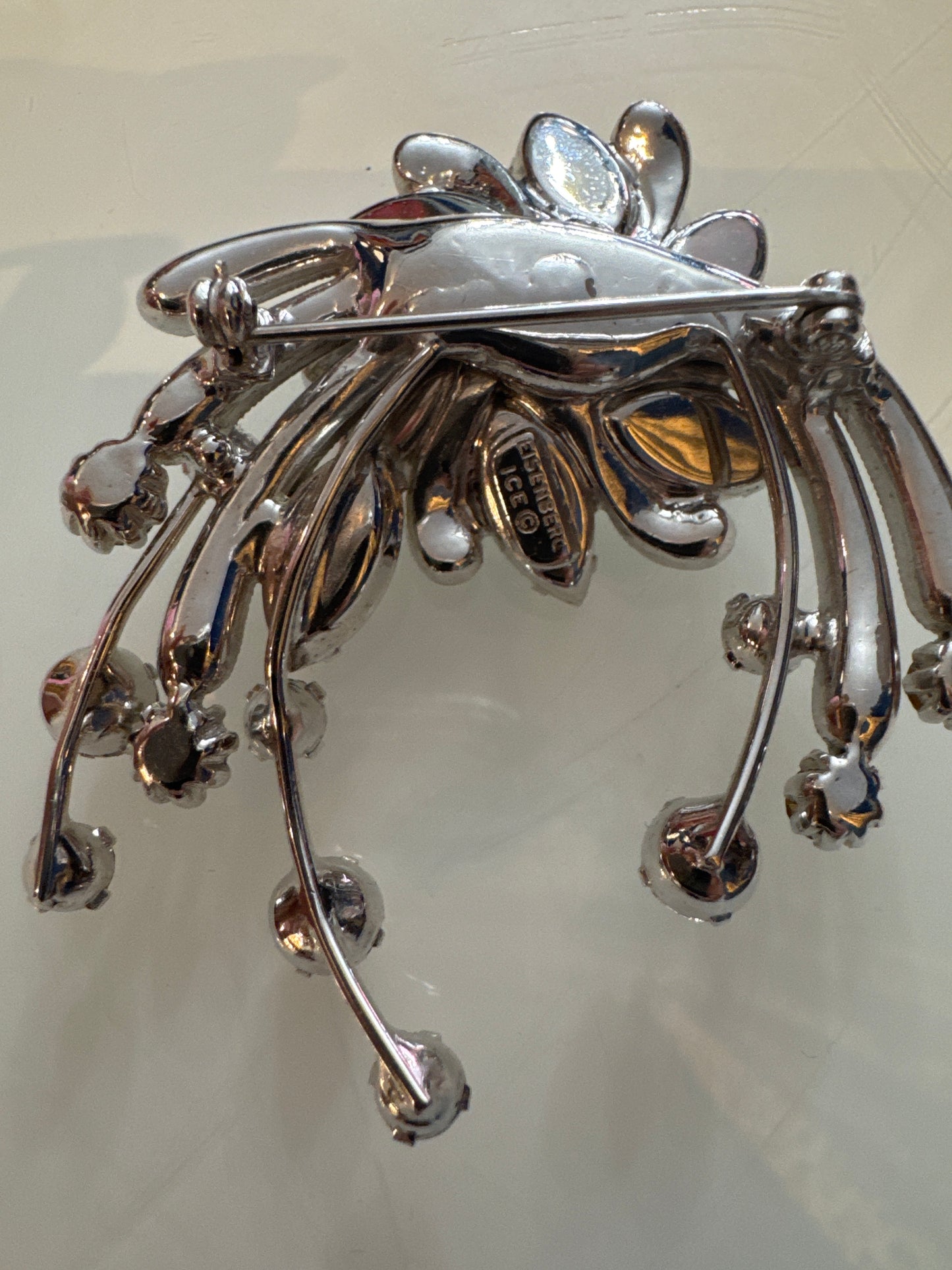 A dramatic mid-century Eisenberg Ice brooch featuring oversized marquise-cut crystals arranged in a radiant floral spray with cascading rhinestone drops. Crafted in rhodium-plated metal with exceptional brilliance and precision.