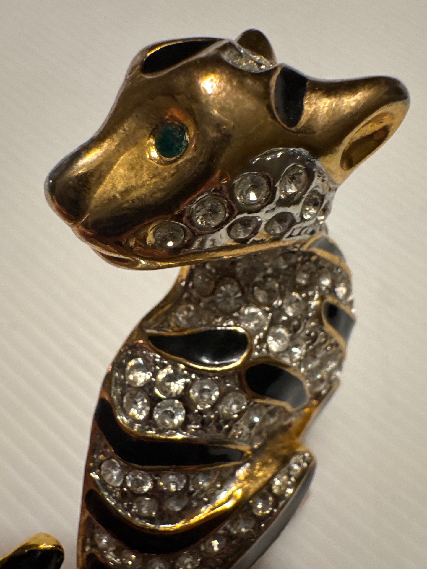 1980s jumbo gold tone, black enamel, and clear rhinestone cheetah brooch with green emerald eyes