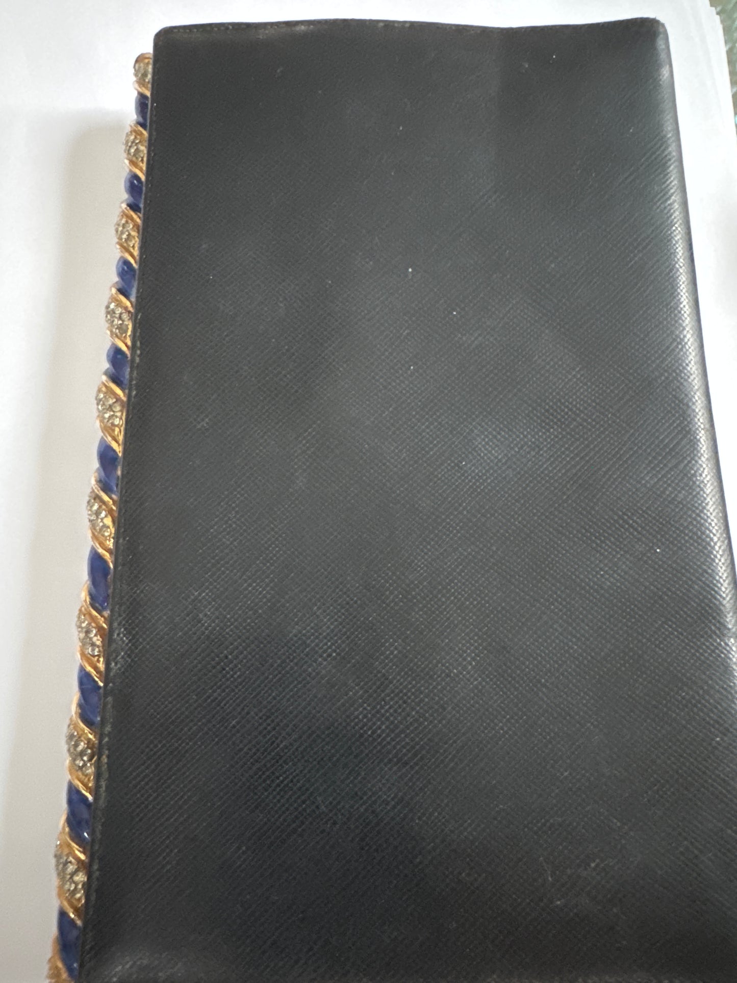 1960s signed Kenneth Lane black leather clutch with decorative blue enamel and rhinestone swirl frame