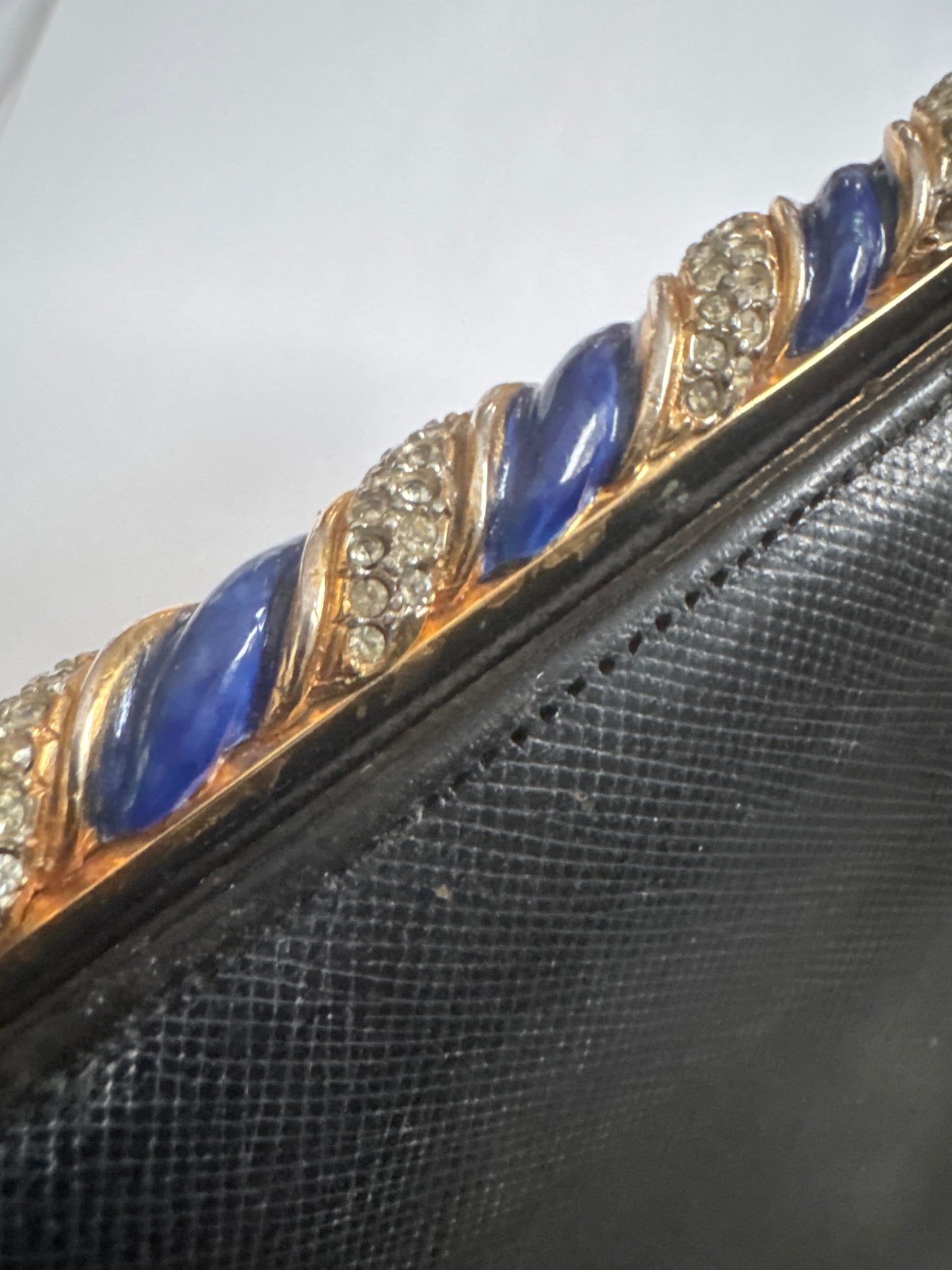 1960s signed Kenneth Lane black leather clutch with decorative blue enamel and rhinestone swirl frame
