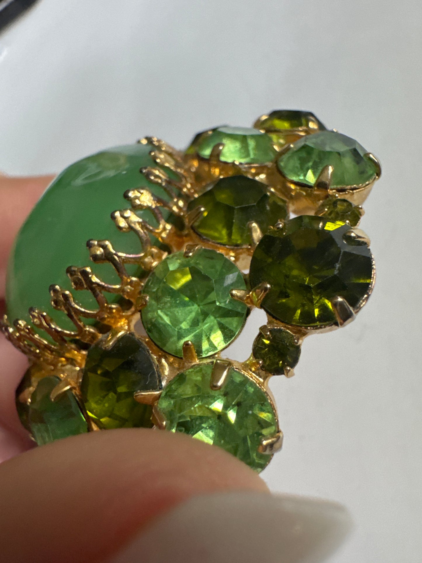 Beautiful 1960s signed PAULINE RADER rhinestone brooch in varying shades of green and olivine. Center stone is marblized green cabochon.