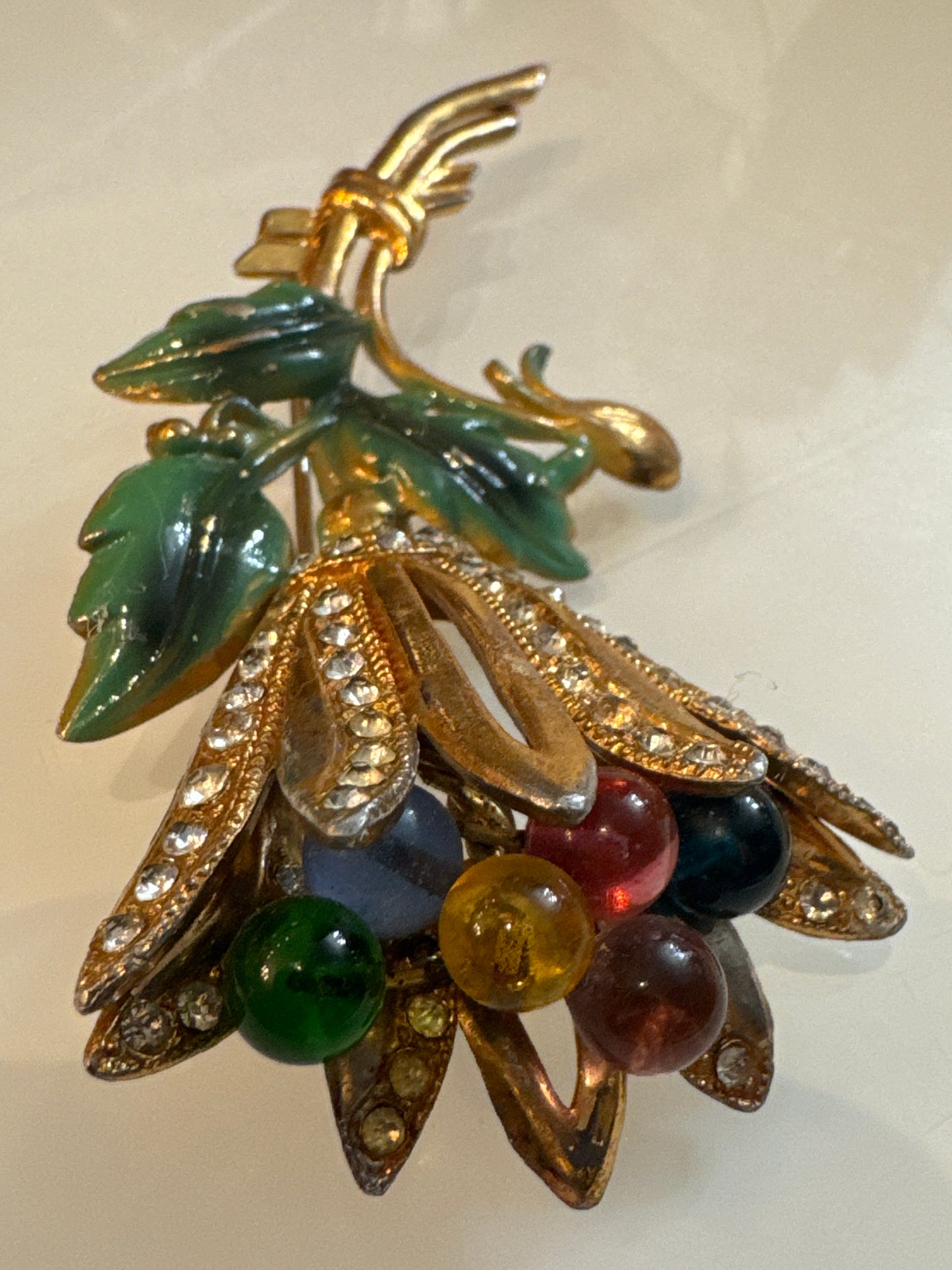 Coro floral spray brooch, late 1950s–early 1960s, featuring molded lucite leaves, multicolored glass bead berries, and rhinestone-set gold-tone petals. Hand-assembled with open architectural construction.