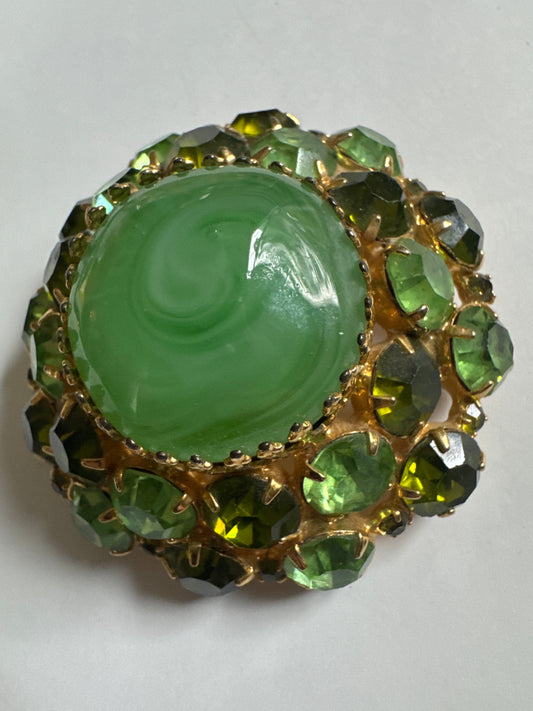 Beautiful 1960s signed PAULINE RADER rhinestone brooch in varying shades of green and olivine. Center stone is marblized green cabochon.