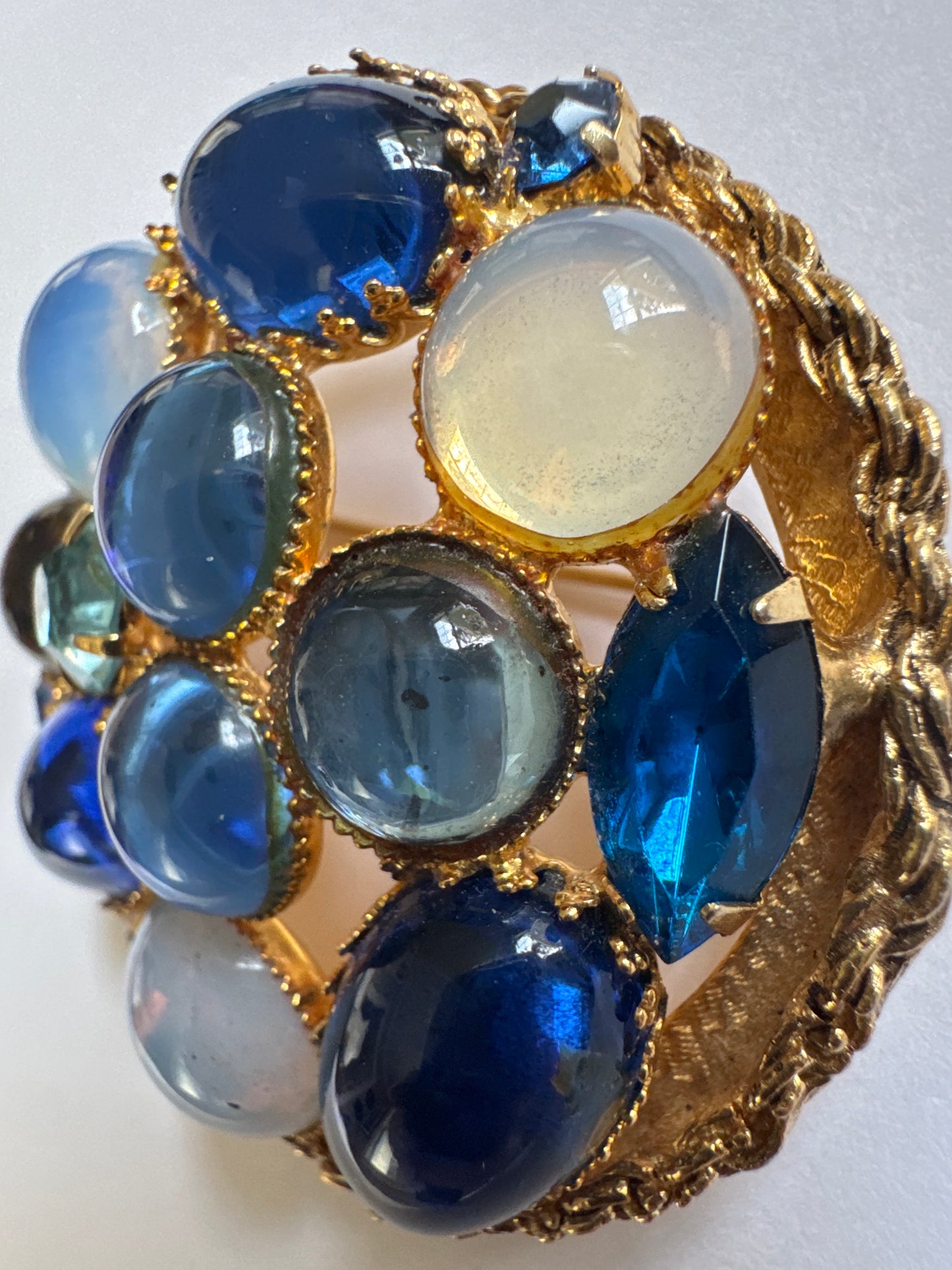 Gorgeous 1950s brooch featuring a mix of luminous blue Czech glass cabochons ranging from milky moonstone tones to deep sapphire hues, plus some cut rhinestones for additional depth