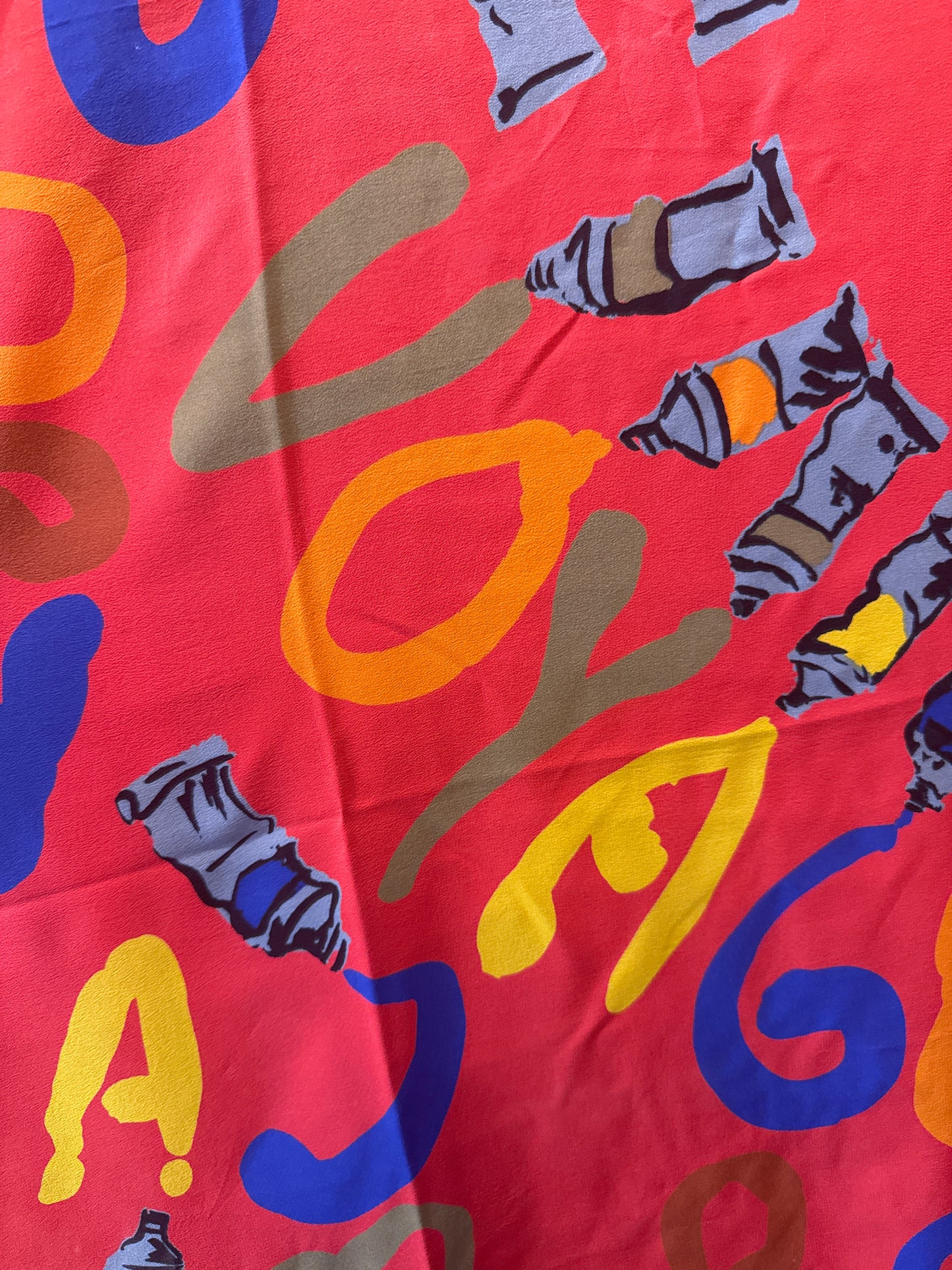 Vintage early 1990s Louis Vuitton red voyage silk scarf. Louis Vuitton “Le Temps d’un Voyage” scarf  is by Italian designer/architect Gae Aulenti, with scattered paint tubes with graffiti-style lettering and hand rolled edges.