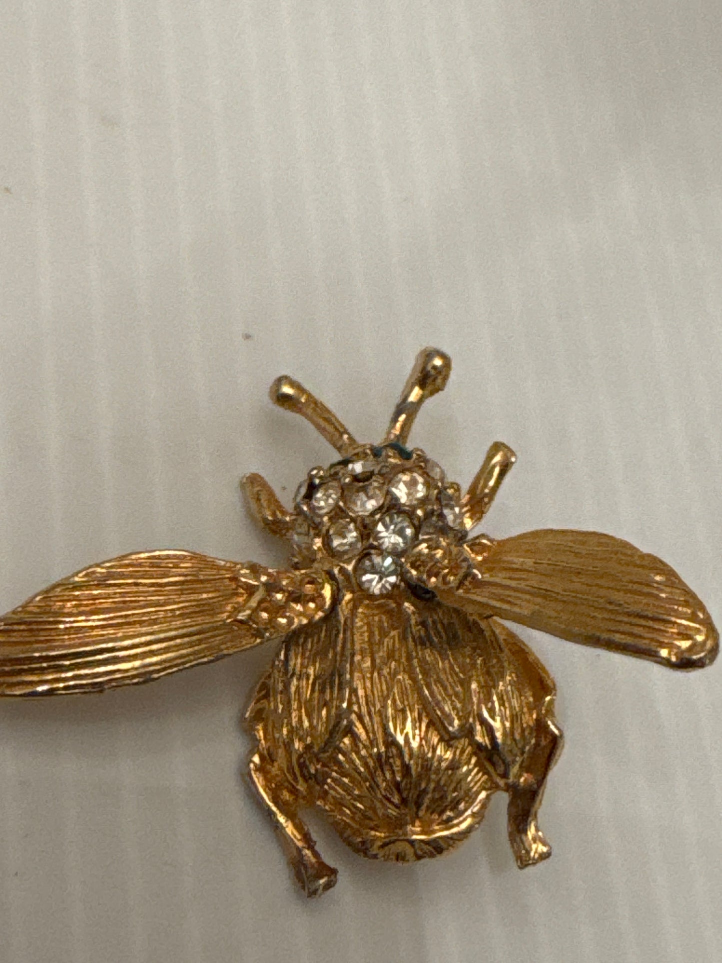 Unsigned vintage trembler brooch, attributed to Hattie Carnegie, circa late 1940s. Identified by its sculptural gold-tone body, ribbed wings, green crystal eyes, and classic Carnegie tremble construction.