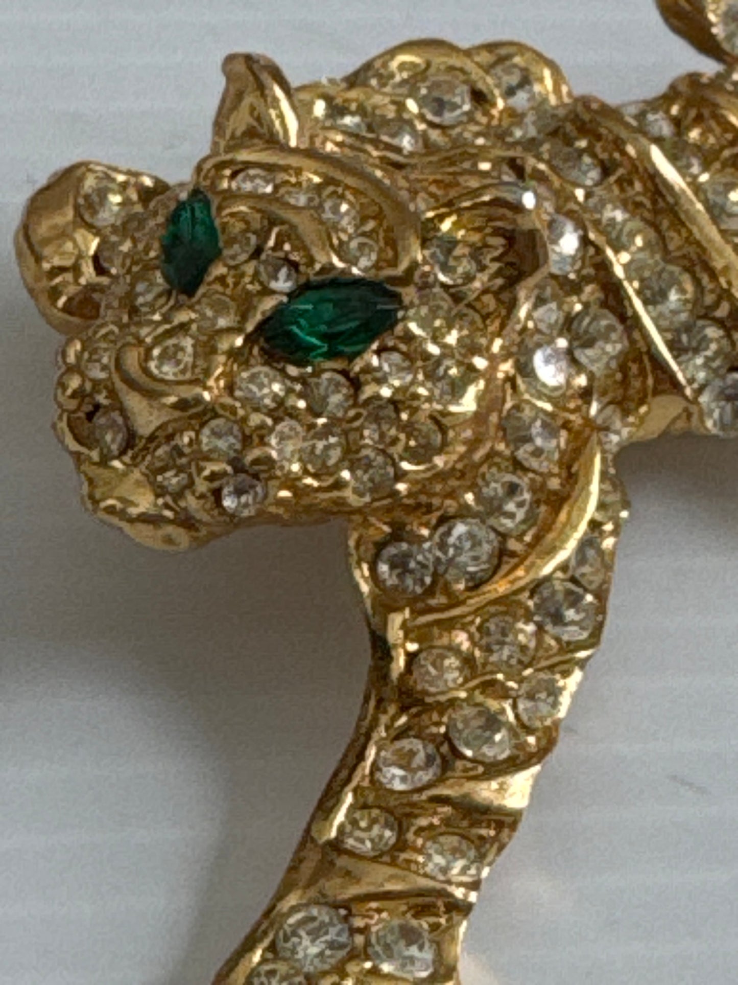 1980s gold tone rhinestone cheetah brooch with green emerald eyes