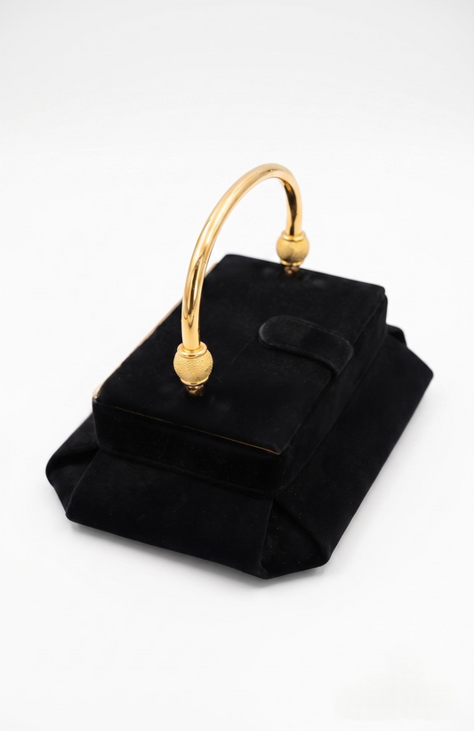 Sophisticated vintage bag in a one of a kind style. This handbag has velvety suede exterior. Pillbox design has art deco vibes. Gilt frame adds structure to the lid and body. Pleated corners. Gold tone decorative hinged handle. Tab with snap closure.