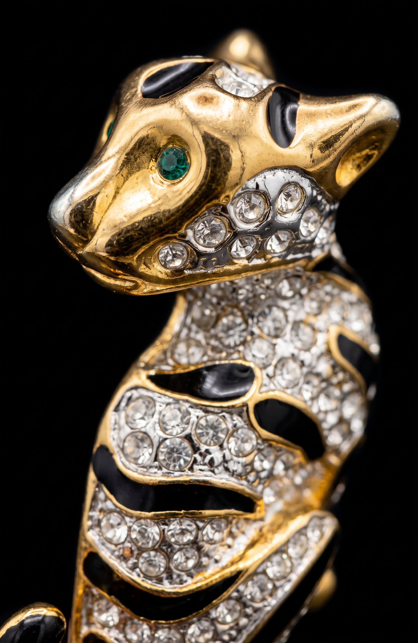 1980s jumbo gold tone, black enamel, and clear rhinestone cheetah brooch with green emerald eyes