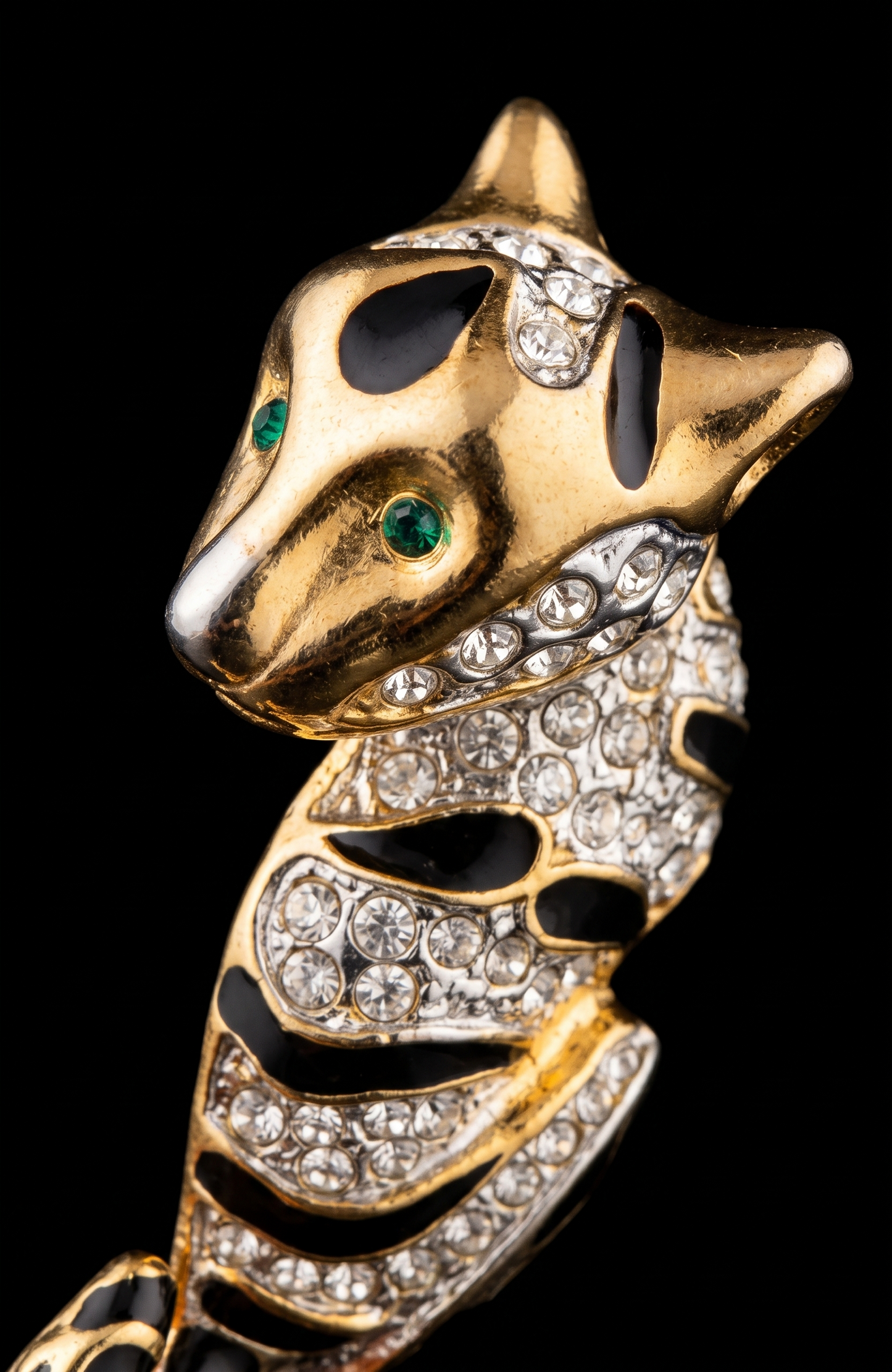 1980s jumbo gold tone, black enamel, and clear rhinestone cheetah brooch with green emerald eyes