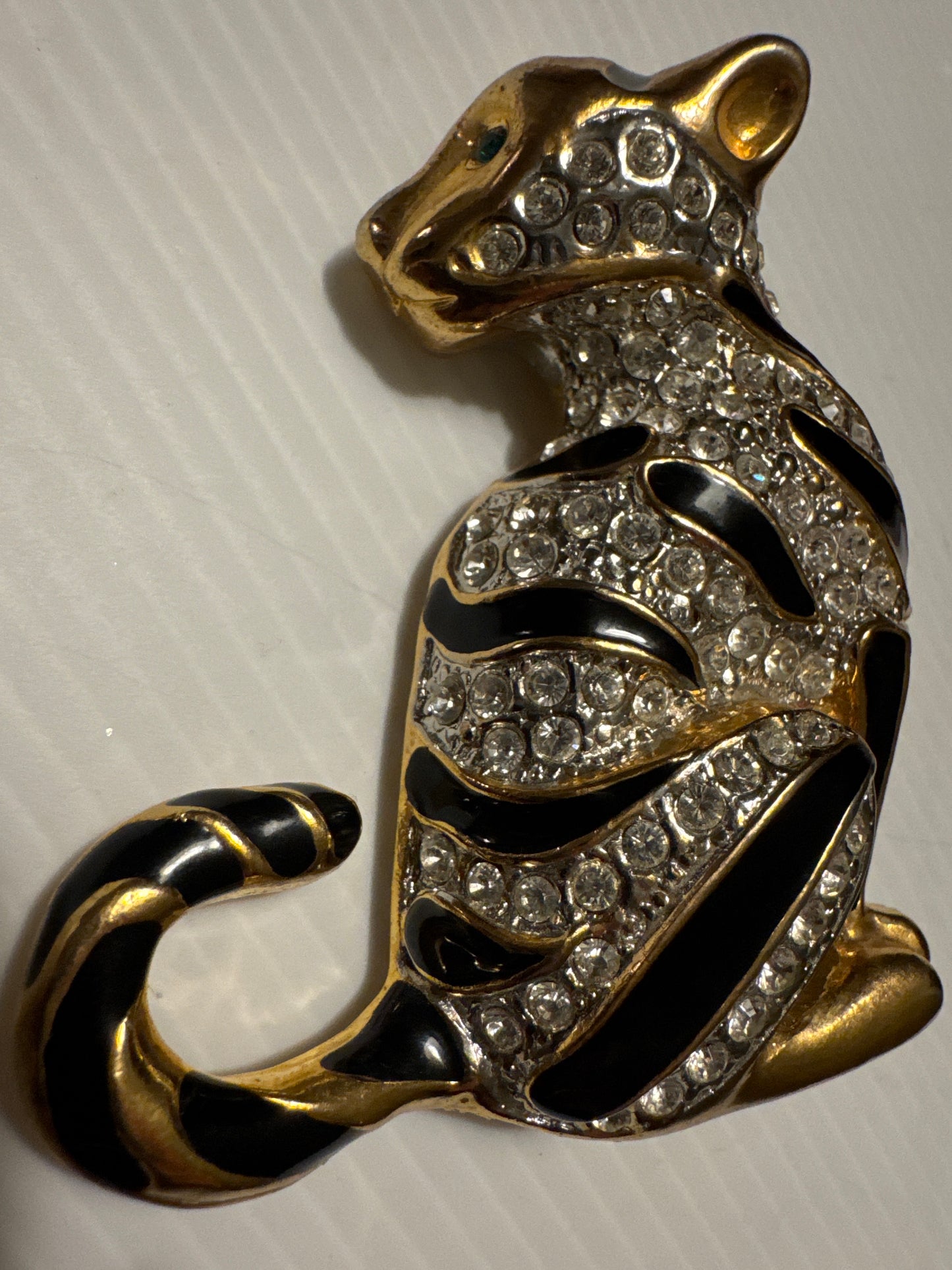 1980s jumbo gold tone, black enamel, and clear rhinestone cheetah brooch with green emerald eyes