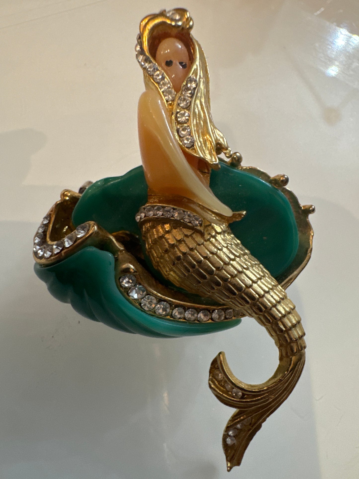 Attributed Hattie Carnagie mermaid brooch circa1960.
Carved lucite figure and wave, hand-set rhinestones, sculptural gold-tone metal. Unsigned, a strong example of mid-century fantasy figural jewelry.