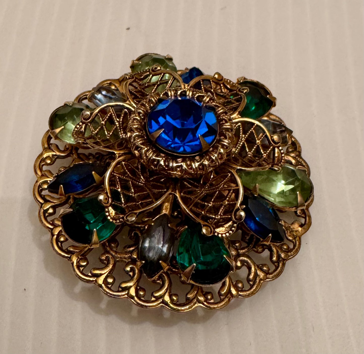 Beautiful 1950s gold tone filigree green and blue rhinestone round brooch