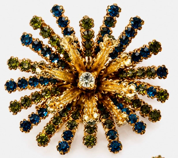 1960s multi layered starburst brooch with green blue and clear rhinestones on both sides of the starburst. Rare piece.