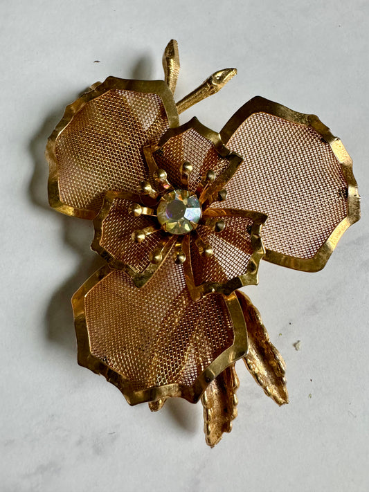 Beautiful gold tone mesh flower brooch with rhinestone center.