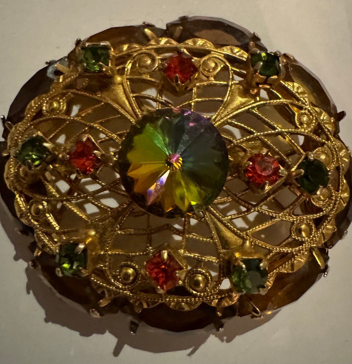 1950s Rivoli watermelon stone and filigree gold tone brooch. Note how center stone changes color in the light