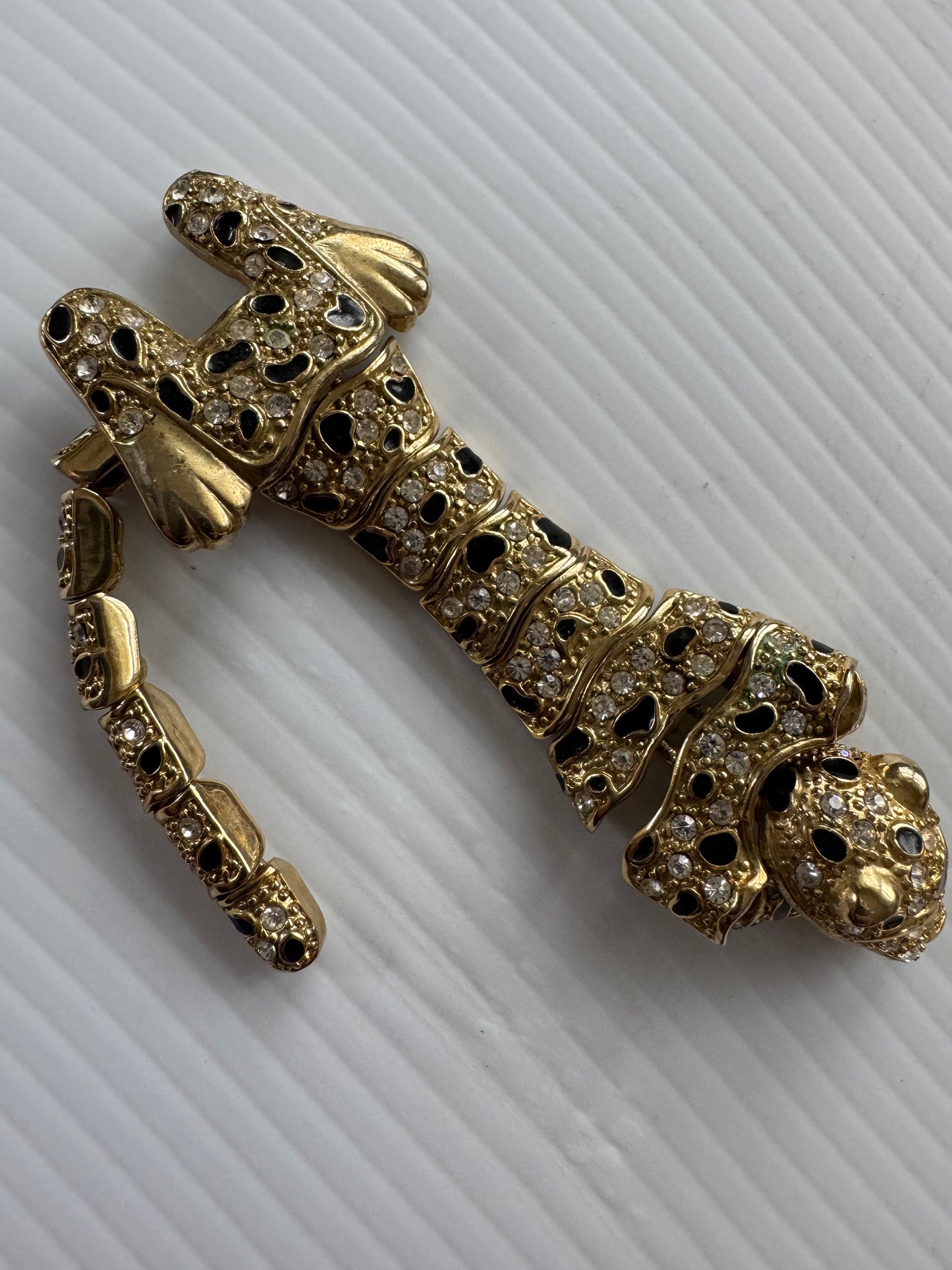 Vintage articulated leopard shoulder brooch in gold tone with black enamel and green rhinestone eyes