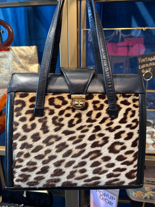 Fantastic 1960s faux leopard fur and black leather handbag. Beautiful interior hardware with three roomie compartments.