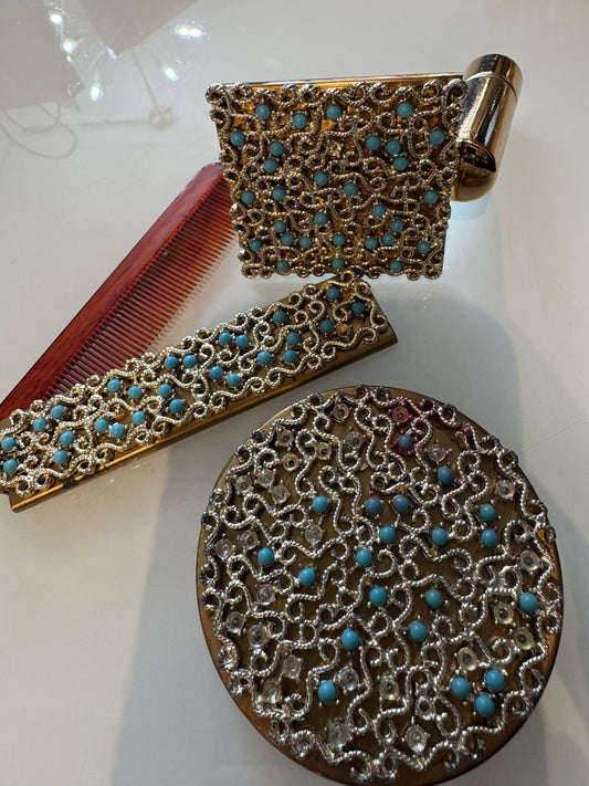 1950s vintage three-piece make up set. Includes decorative powder compact, foldable comb and refillable lipstick holder with mirror. See images for a couple of missing stones